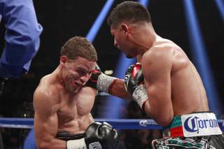 Jonathan Oquendo, left, takes a punch from Abner Mares during their featherweight fight Saturday, July 12, 2014 at the MGM Grand Garden Arena.