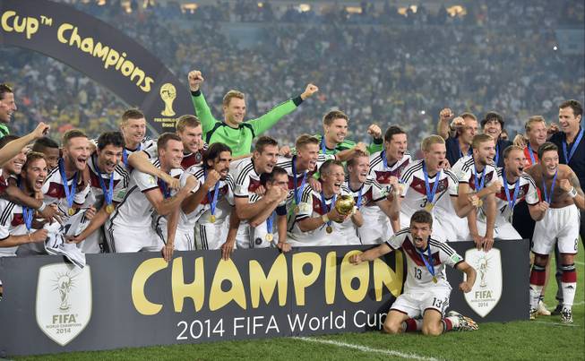 German players celebrate with the trophy after the World Cup final soccer match between Germany and Argentina at the Maracana Stadium in Rio de Janeiro, Brazil, Sunday, July 13, 2014. Germany won the match 1-0.