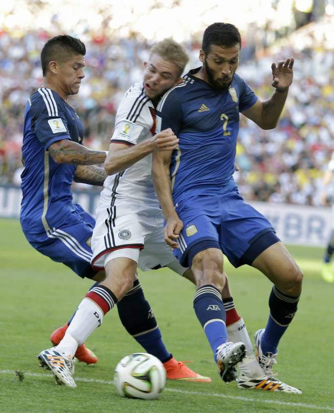 Germany's Christoph Kramer gets hit in the face by Argentina's Ezequiel Garay shoulder (2) while pinned between Garay and Marcos Rojo during the World Cup final soccer match between Germany and Argentina at the Maracana Stadium in Rio de Janeiro, Brazil, Sunday, July 13, 2014.