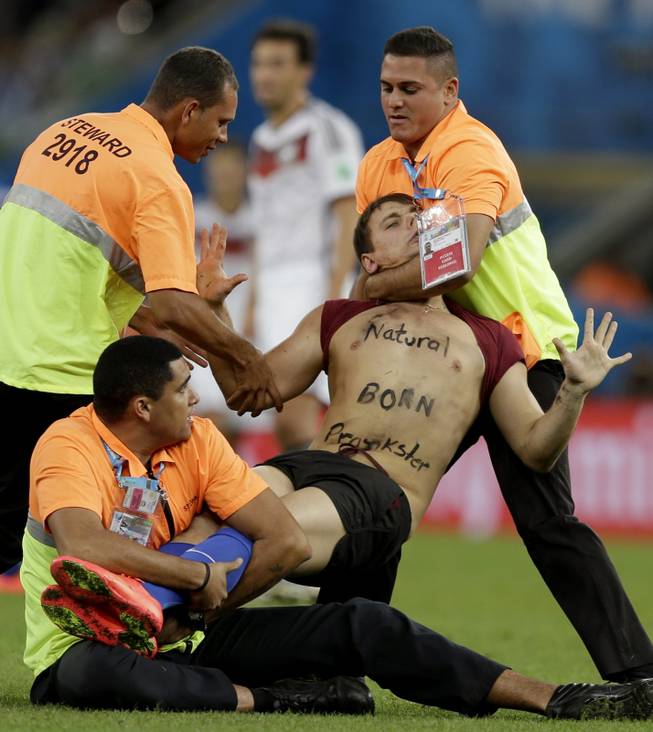 A spectator who ran on to the pitch during the World Cup final soccer match between Germany and Argentina is subdued by security personnel at the Maracana Stadium in Rio de Janeiro, Brazil, Sunday, July 13, 2014.