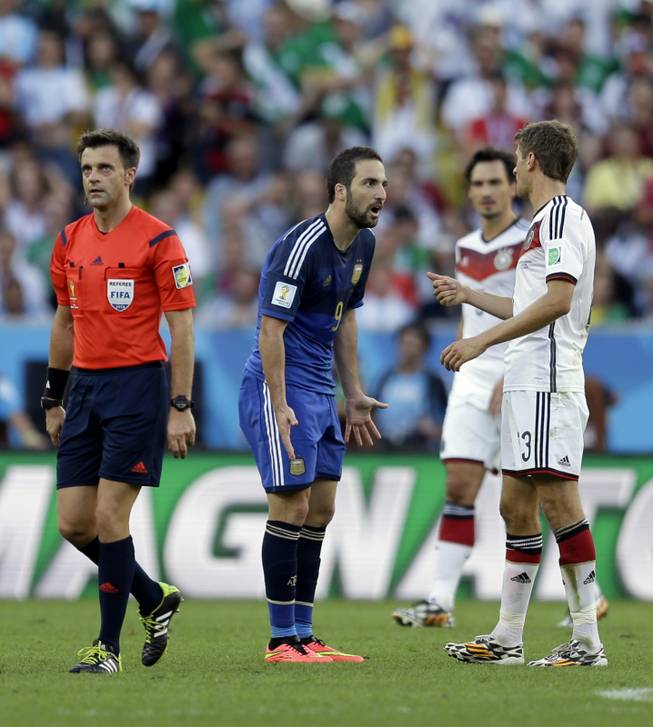 Referee Nicola Rizzoli from Italy walks away while Argentina's Gonzalo Higuain has an argument with Germany's Thomas Mueller, right, during the World Cup final soccer match between Germany and Argentina at the Maracana Stadium in Rio de Janeiro, Brazil, Sunday, July 13, 2014.