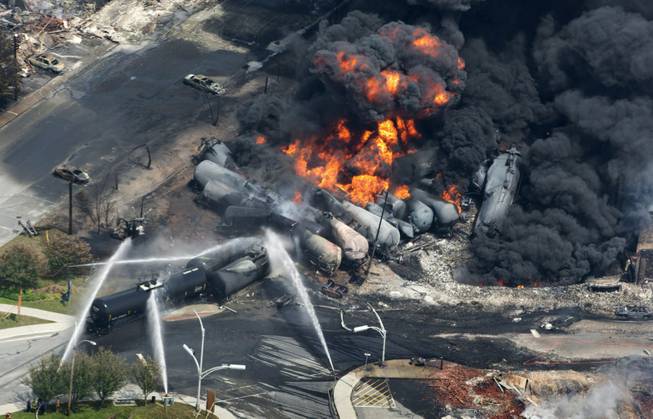 This July 6, 2013, file photo shows smoke rising from railway cars carrying crude oil after derailing in downtown Lac Megantic, Quebec. A string of fiery train derailments across the country has triggered a high-stakes and behind-the-scenes campaign to shape how the government responds to calls for tighter safety rules. Billions of dollars are riding on how these rules are written, and lobbyists from the railroads, tank car manufacturers and the oil, ethanol and chemical industries have met more than a dozen times since mid-May 2014 with officials at the White House and the Pipeline and Hazardous Materials Safety Administration. Their universal message: Don’t make us pay for increased safety — that’s another industry’s problem.