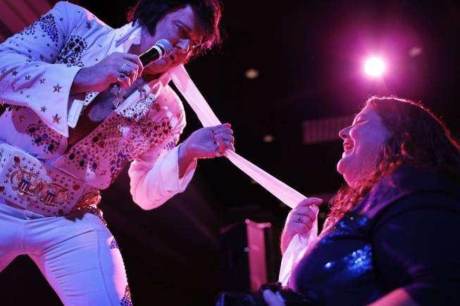 In this July 12, 2014, photo, Elvis tribute artist Jim Westover, left, of Arizona City, Ariz., gives a scarf to fan Juanita Curtice, of Woodbridge, Va., during the Las Vegas Elvis Festival in Las Vegas. Some three dozen Elvis tribute artists took their gyrating hips and curled lips to the stage over the weekend to see who could do the most convincing portrayal.