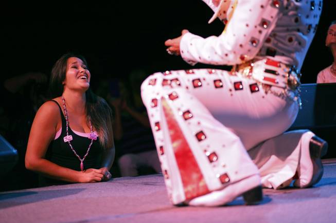 In this July 12, 2014, photo, Yvonne Garcia, of Midland, Texas, watches an Elvis tribute artist perform during the Las Vegas Elvis Festival in Las Vegas. Some three dozen Elvis tribute artists took their gyrating hips and curled lips to the stage over the weekend to see who could do the most convincing portrayal.