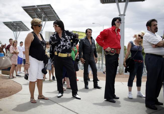 In this July 10, 2014 photo, Elvis tribute artists participating in the Las Vegas Elvis Festival wait in line to take pictures in front of the "Welcome to Las Vegas" sign in Las Vegas. Several of the tribute artists took a bus tour around Las Vegas during the convention.