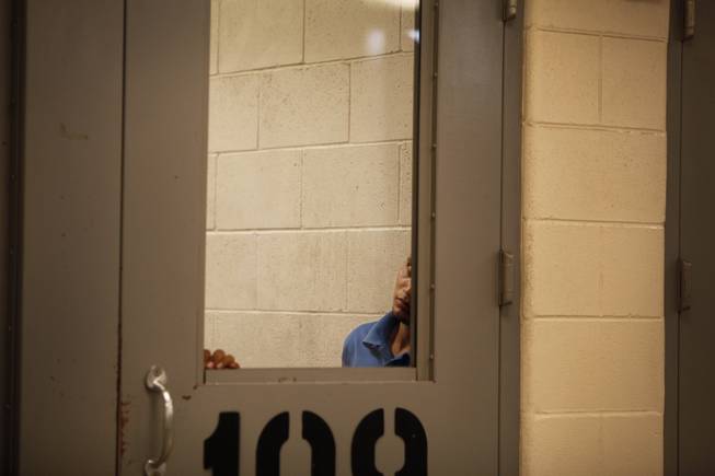An immigrant peers out from a detention area in McAllen, Texas, Tuesday, July 15, 2014 at the McAllen Border Patrol Station. A solution for the growing crisis of tens of thousands of unaccompanied children showing up at the U.S.-Mexico border has been elusive.