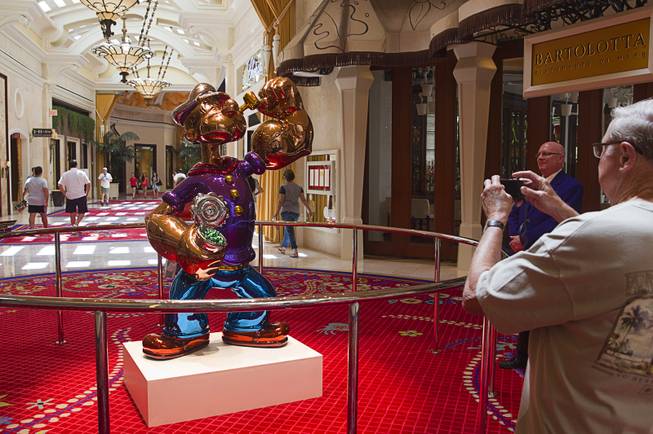 A man takes a photo of the Popeye sculpture in the Wynn Esplanade Thursday, July 17, 2014. The stainless steel sculpture, by American artist Jeff Koons, was purchased at auction for $28.2 million.