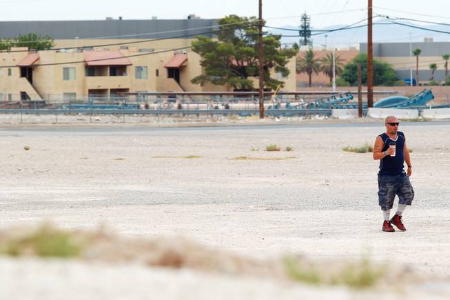 A man carries a drink across a vacant lot on the south end of the Strip Tuesday, July 15, 2014.
