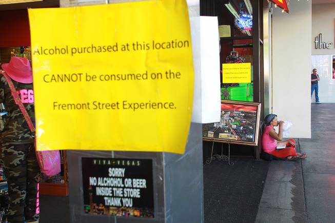 A woman drinks from a can in a bag while sitting outside a store at the Fremont Street Experience Thursday, July 17, 2014.