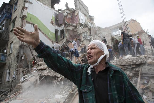 AP10ThingsToSee - Igor Chernetsov, whose wife was killed in a building demolished by an airstrike, gestures near the collapsed structure in Snizhne, 100 kilometers east of Donetsk, eastern Ukraine, Tuesday, July 15, 2014. At least nine civilians were killed in the attack, rescue workers said. 