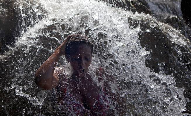 AP10ThingsToSee - A voodoo pilgrim bathes in a waterfall believed to have purifying powers during the annual celebration in Saut d' Eau, Haiti, Wednesday, July 16, 2014.