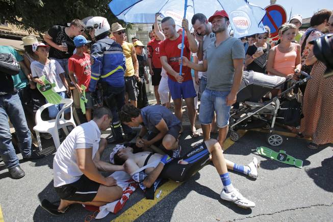 Spectators shield Spain's David De La Cruz Melgarejo from the sun after he crashed when riding in the breakaway in Oingt, during the twelfth stage of the Tour de France cycling race over 185.5 kilometers (115.3 miles) with start in Bourg-en-Bresse and finish in Saint-Etienne, France, Thursday, July 17, 2014. De La cruz had to withdraw from the race because of his injuries. 