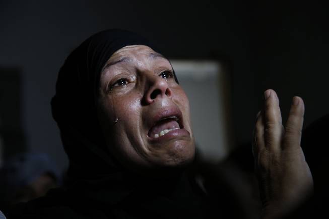 AP10ThingsToSee - A Palestinian mourner cries after the bodies of Mousa Abu Muamer, 56, and his son Saddam, 27, were brought in for their funeral on Monday, July 14, 2014, in the Gaza Strip. The two were killed in an overnight Israeli missile strike at their house in the outskirts of the town of Khan Younis, southern Gaza Strip. 