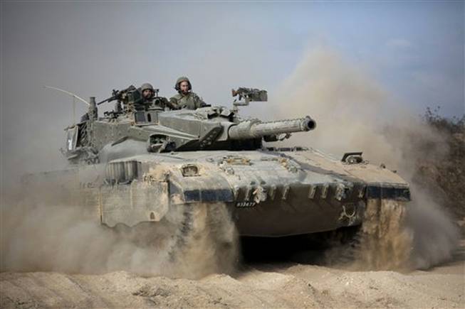 An Israeli tank moves into position near the Israel and Gaza border, Friday, July, 18, 2014. Israeli troops pushed deeper into Gaza on Friday to destroy rocket-launching sites and tunnels. Israel launched the operation late Thursday.