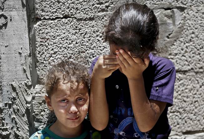 In this Thursday, July 17, 2014, file photo, Palestinian siblings Maria Abdel Aal, 4, right, and Misk, 3, left, cry as the body of their relative Bashir Abdel Aal, killed in an overnight Israeli missile strike in Rafah, southern Gaza Strip, is carried away from the family house, during his funeral. Minors make up almost one-fifth of those killed in Israel's 11-day bombardment of Hamas targets in densely populated Gaza, where half the population is under the age of 18.