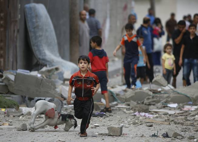 A Palestinian child runs on debris from a destroyed house after an overnight Israeli strike in Beit Lahiya, northern Gaza Strip, on Saturday, July 19, 2014.