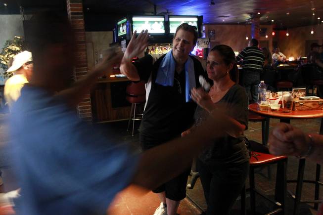 Stacy Bromberg and Lisa Boshart give Mike Brooks a high five during a meeting of the Las Vegas Darts league Wednesday, July 2, 2014 at the Crowbar.