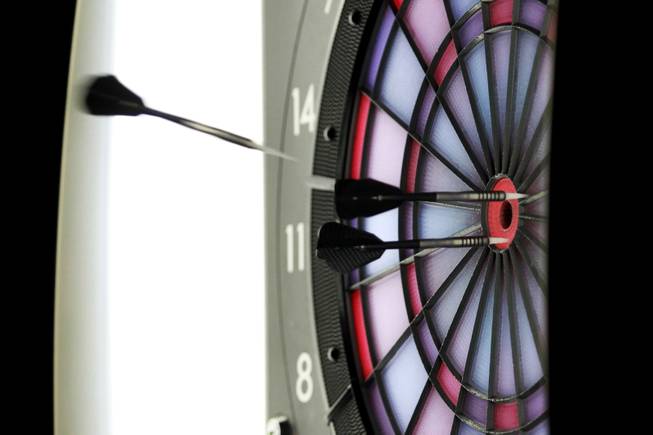 A dart sails into a dart board during a meeting of the Las Vegas Darts league Wednesday, July 2, 2014 at the Crowbar.
