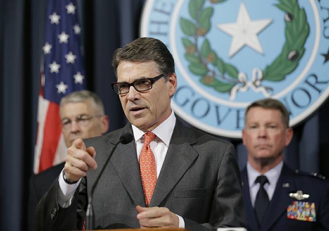 Gov. Rick Perry, center, speaks during a news conference in the Governor's press room, Monday, July 21, 2014, in Austin, Texas. 