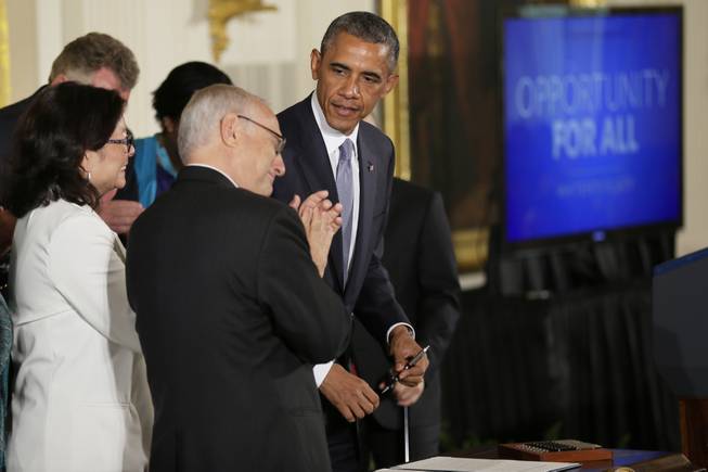 Rabbi David Saperstein, left, claps as President Barack Obama approaches to sign an executive order to protect LGBT employees from federal workplace discrimination in the East Room of the White House Monday, July 21, 2014, in Washington. Obama's executive order signed Monday prohibits discrimination against gay and transgender workers in the federal government and its contracting agencies, without a new exemption that was requested by some religious organizations.
