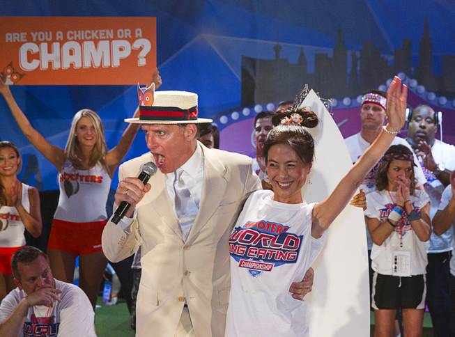 Emcee George Shea introduces fourth place finisher Juliet Lee during the 2014 Hooters "World-Wide Wing Eating Championship" at the Hard Rock pool Tuesday, July 22, 2014.
