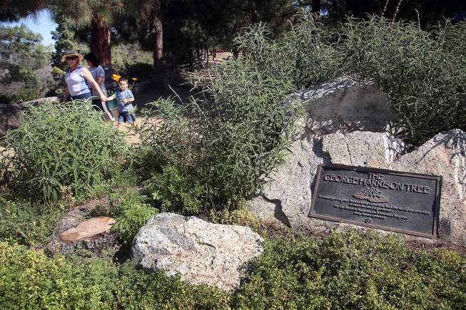 Visitors walk past a plaque marking the George Harrison Tree in Griffith Park on Tuesday, July 22, 2014, in Los Angeles.