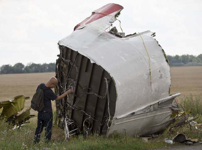 A Malaysian air crash investigator takes pictures of wreckage at the crash site of Malaysia Airlines Flight 17 near the village of Hrabove, eastern Ukraine, Tuesday, July 22, 2014. 