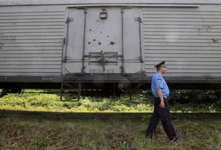 A police officer walks past a refrigerated train loaded with bodies of the passengers of Malaysian Airlines flight MH17 at Kharkiv railway station, Ukraine, Tuesday, July 22, 2014. The train carrying the remains of people killed in the Malaysia Airlines crash arrived in the eastern Ukrainian city of Kharkiv on Tuesday on their way to the Netherlands, a journey which has been agonizingly slow for relatives of the victims. 