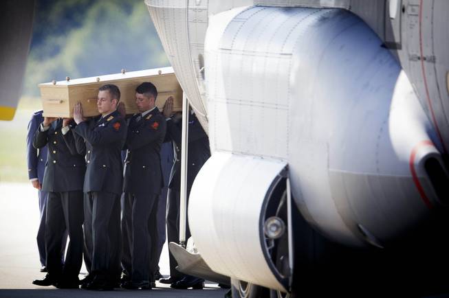 Pallbearers carry a coffin out of a military transport plane during a ceremony to mark the return of the first bodies, of passengers and crew killed in the downing of Malaysia Airlines Flight 17, from Ukraine at Eindhoven military air base, Eindhoven, Netherlands, Wednesday, July 23, 2014. After being removed from the planes, the bodies are to be taken in a convoy of hearses to a military barracks in the central city of Hilversum, where forensic experts will begin the painstaking task of identifying the bodies and returning them to their loved ones.