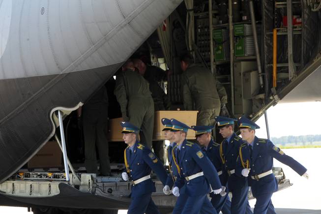 Ukrainian honor guards march away from a cargo plane, as Dutch crew members load a coffin holding the body of one of the Malaysian Airlines plane passengers in Kharkiv airport, Ukraine, Wednesday, July 23, 2014.