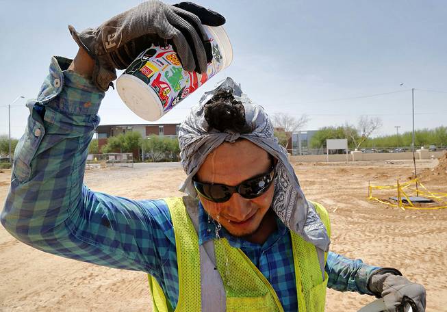 Construction worker Ruben Roman drips water on his head during his lunch break, Thursday, July 24, 2014, at at job site in Phoenix. With Phoenix-area daytime highs hovering around 110 degrees, outdoor activity is minimal throughout the valley. 
