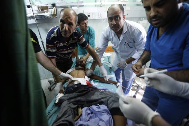 Palestinian medics treat a child wounded in an Israeli strike on a compound housing a U.N. school in Beit Hanoun, in the northern Gaza Strip, at the emergency room of the Kamal Adwan hospital in Beit Lahiya, Thursday, July 24, 2014.