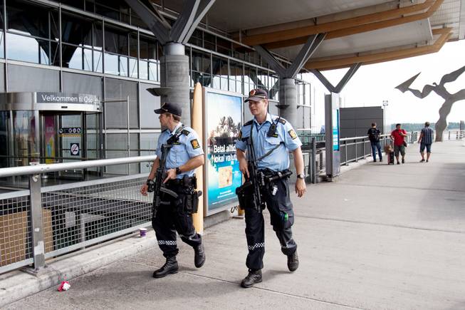 Armed police patrol outside the terminal building at Oslo Airport, Thursday, July 24, 2014. Norway's intelligence service says it has been warned of an imminent "concrete threat" against the nation from people with links to Islamic fighters in Syria.