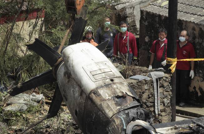 Emergency workers watch an engine lifted from the TransAsia Airways Flight GE222 crash site on the outlying Taiwan island of Penghu, Friday, July 25, 2014. Investigators on Friday were examining wreckage and flight data recorders for clues into a plane crash on the Taiwanese island that killed 48 people.
