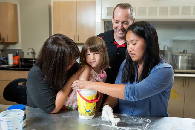 UNLV Professor Brendan O'Toole, top, and Katherine Lau, an undergraduate intern from Rutgers University, right, join Yong Dawson in helping to take measurements from Dawson's 4-year-old daughter Hailey Dawson in O'Toole's lab June 19, 2014 at the University of Nevada, Las Vegas. 