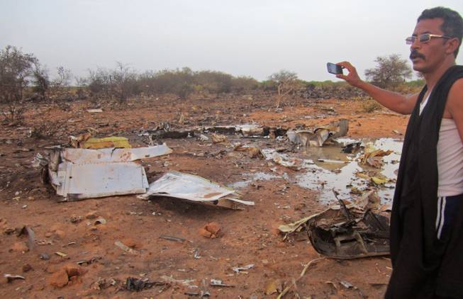 This photo provided on Friday, July 25, 2014, by the Burkina Faso Military shows a man at the site of the plane crash in Mali. French soldiers secured a black box from the Air Algerie wreckage site in a desolate region of restive northern Mali on Friday, the French president said.