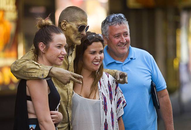 "Las Vegas Gold Statue" Steve McDonald poses with tourists from Chile perform at the Fremont Street Experience Sunday, July 27, 2014.