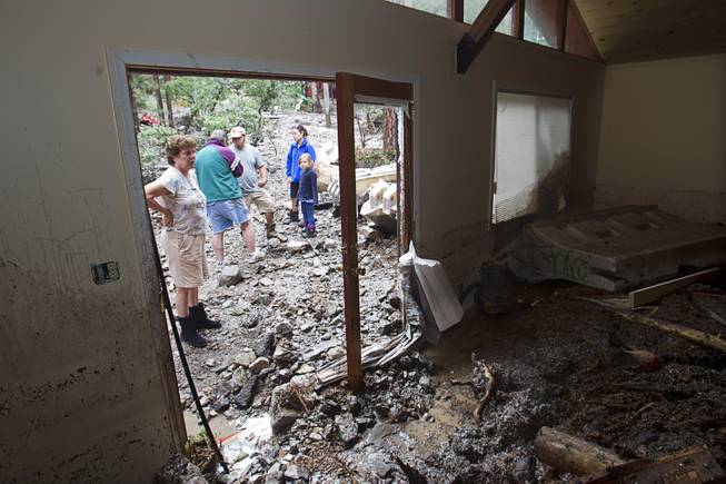 Resident Joyce Luman looks inside a neighbor's home in the Rainbow Subdivision on Mt. Charleston Monday, July 28, 2014. The homeowners were still repairing the home from last year's storm, neighbors said.