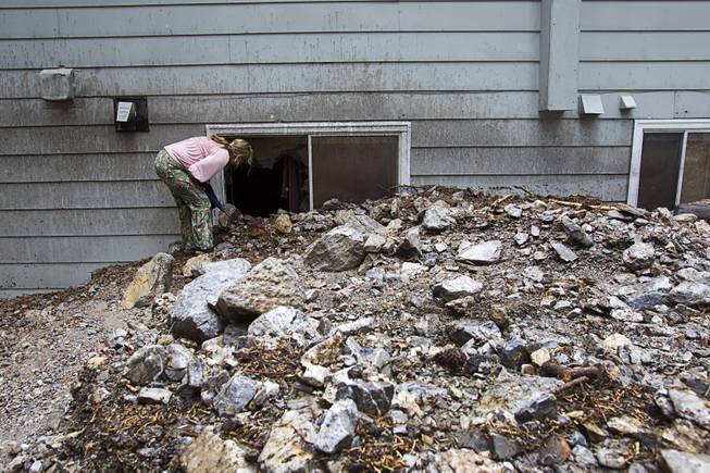 Resident Lynn Thomas looks in a window of a neighbor's home in the Rainbow Subdivision on Mt. Charleston Monday, July 28, 2014. The home suffered major damage from flood water and debris. The neighborhood was hit hard by flooding and debris in runoff last year as well.