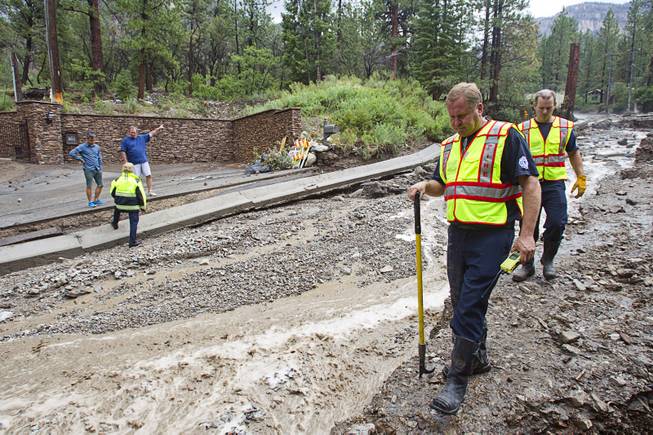 Firefighters inspect damage to Rainbow Canyon Boulevard in the Rainbow Subdivision on Mt. Charleston Monday, July 28, 2014. The neighborhood was hit hard by flooding and debris in runoff last year as well.