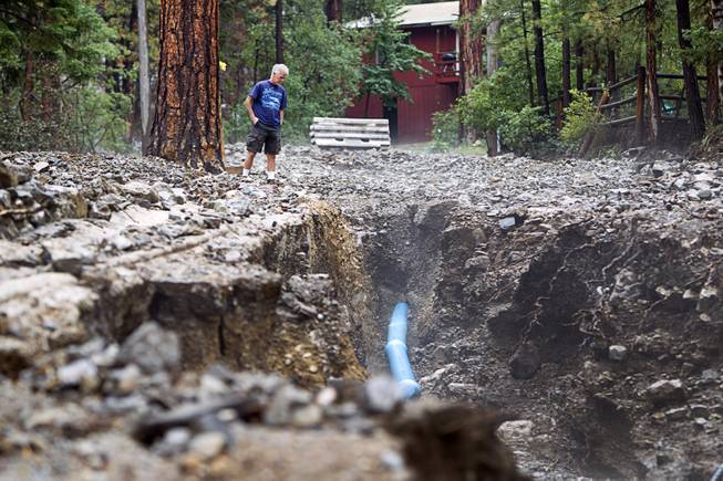 Resident Mike Saulpaw looks over damage to Rainbow Canyon Boulevard in the Rainbow Subdivision on Mt. Charleston Monday, July 28, 2014. The neighborhood was hit hard by flooding and debris in runoff last year as well.