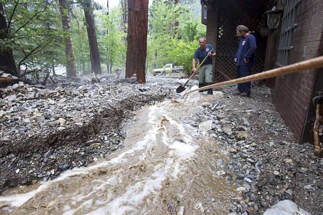 Duffy Grismanauskas, left, talks with volunteer firefighter Jim Tiscareno as he tries to keep runoff from his home in the Rainbow Subdivision on Mt. Charleston Monday, July 28, 2014. The neighborhood was hit hard by flooding and debris in runoff last year as well.