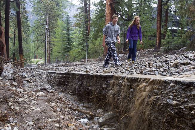 Residents Austin Thomas, 15, and Reznor Weist, 13, walk along a flood-damaged Rainbow Canyon Boulevard in the Rainbow Subdivision on Mt. Charleston Monday, July 28, 2014. The neighborhood was hit hard by flooding and debris in runoff last year as well.