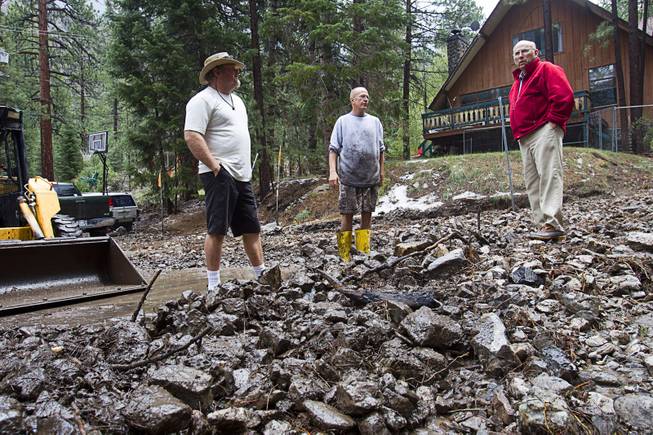 Contractor Tony Cuglietta, left, talks with residents Steve Kammer, and Bill Beeler in a street filled with debris in the Rainbow Subdivision on Mt. Charleston Monday, July 28, 2014. Cuglietta has been working on a barrier for Kammer's home which suffered only mild water damage, Kammer said.