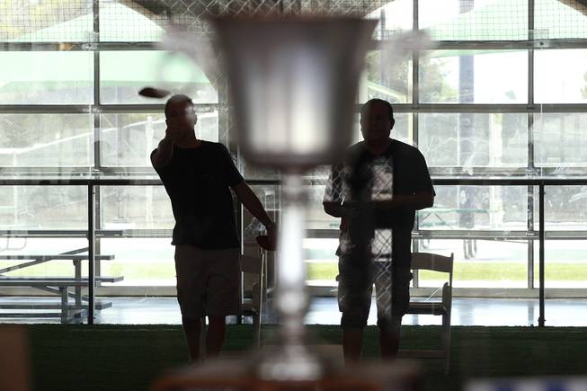 Players are seen behind a window and trophy during a Cornhole tournament Saturday, July 26, 2014.