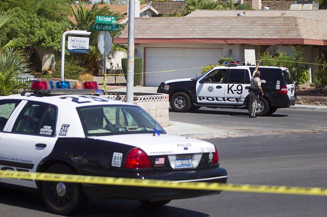 A Metro Police officer lifts crime scene tape over a K9 SUV in a neighborhood near Tropicana Avenue and Sandhill Road after an officer-involved shooting Tuesday, July 29, 2014. The shooting was related to a home invasion, according to Metro Police.