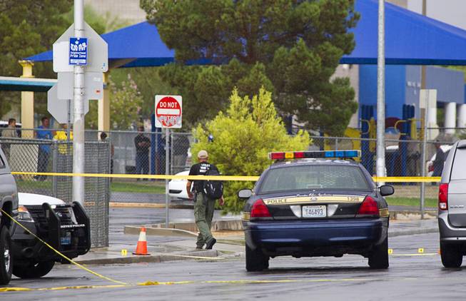 A Metro Police officer walks by evidence markers on the street at the scene of an officer-involved-shooting near Pecos and Alexander roads August 3 , 2014.