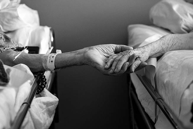 In this July 2014 photo provided by their granddaughter Melissa Stone, Don Simpson, 90, and his wife Maxine, 87, hold hands from adjoining hospice beds in Sloan's home in Bakersfield, Calif. The couple, married 62 years, died four hours apart July 21, 2014, while lying next to each other, their family said. 