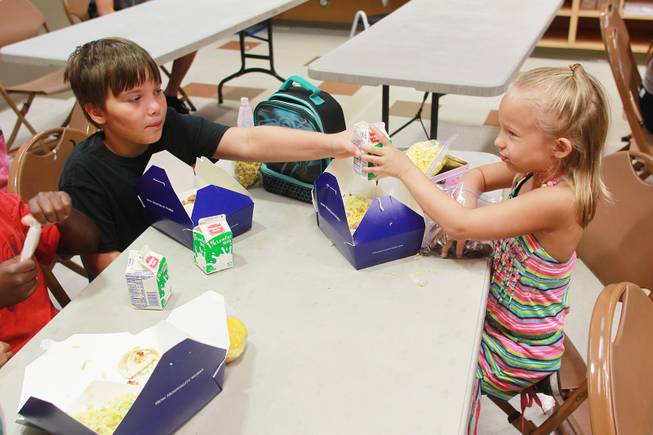 Aidan Beshara hands a carton of milk to his sister LillyMay Beshara during a summer day camp at the Stupak Community Center Tuesday, Aug. 5, 2014.