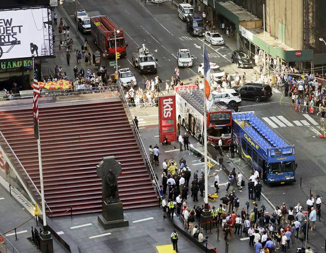 Two double-decker tour buses sit at 47th Street and 7th Avenue in Times Square after colliding Tuesday, Aug. 5, 2014, in New York. 